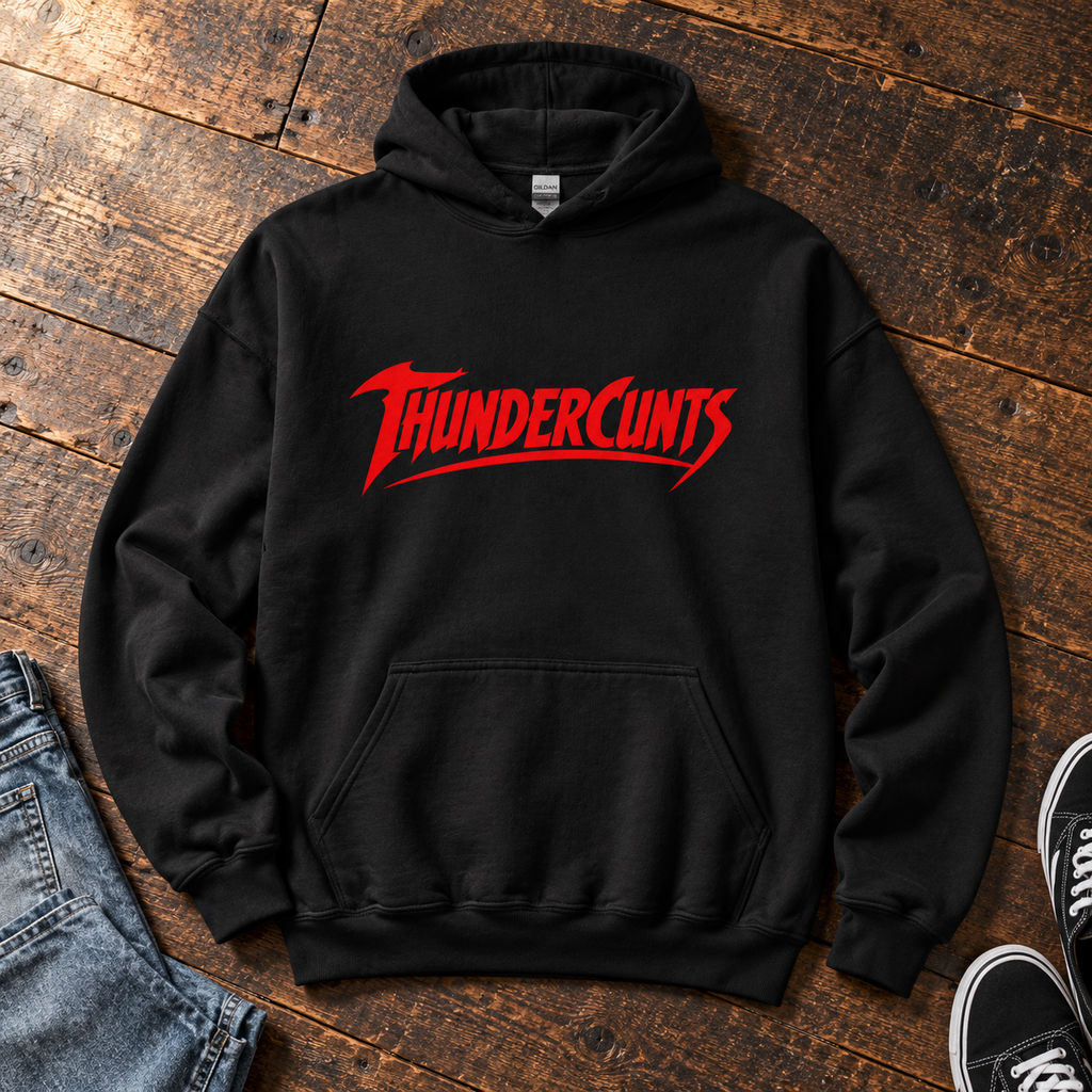 Black Thundercunts hoodie with red slogan lettering, laid flat on wooden floorboards.
